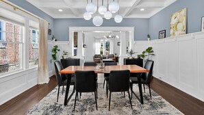 Un espace repas avec une table en bois, des chaises noires et un luminaire suspendu.