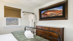 A bedroom with a bed, a dresser, a window with a view, a robe, and a framed picture on the wall. - Panoramic Mountain Views + Private Hot Tub — Your Ultimate Shenandoah Valley Escape (Raphine)