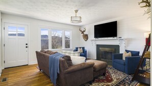 A living room with a fireplace, a mounted deer head, and a television. - Panoramic Mountain Views + Private Hot Tub — Your Ultimate Shenandoah Valley Escape (Raphine)