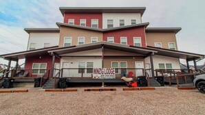 Un edificio de dos pisos con un letrero que dice 'WINZIG LODGE' y un número de contacto.