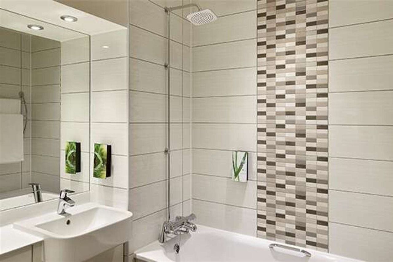 A modern bathroom with a large mirror, two sinks, a bathtub, and a shower.