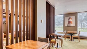 Een restaurant met houten meubels, een groot raam en een schilderij van een vuurtoren.