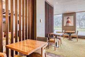 A restaurant with wooden furniture, a large window, and a lighthouse painting. - Premier Inn Plymouth City Centre (Plymouth)