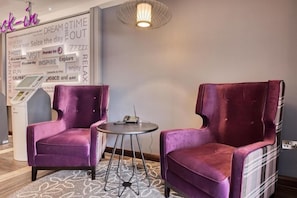 A room with two purple velvet armchairs, a small round table, a wall with motivational phrases, and a modern pendant light. - Premier Inn Plymouth City Centre (Plymouth)