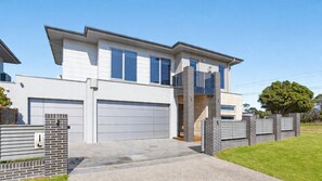 A modern two-story house with a garage, a balcony, and a brick wall. - The Coral Esplanade with Pool (Mornington)
