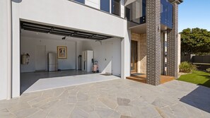 Ein modernes Haus mit Garage, einer Steinterrasse und einer Ziegelstütze.