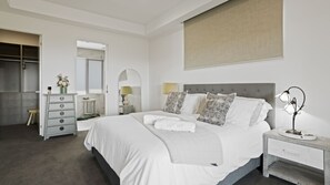Ein Schlafzimmer mit einem Bett, Nachttischen, einem Schminktisch und einem Spiegel.