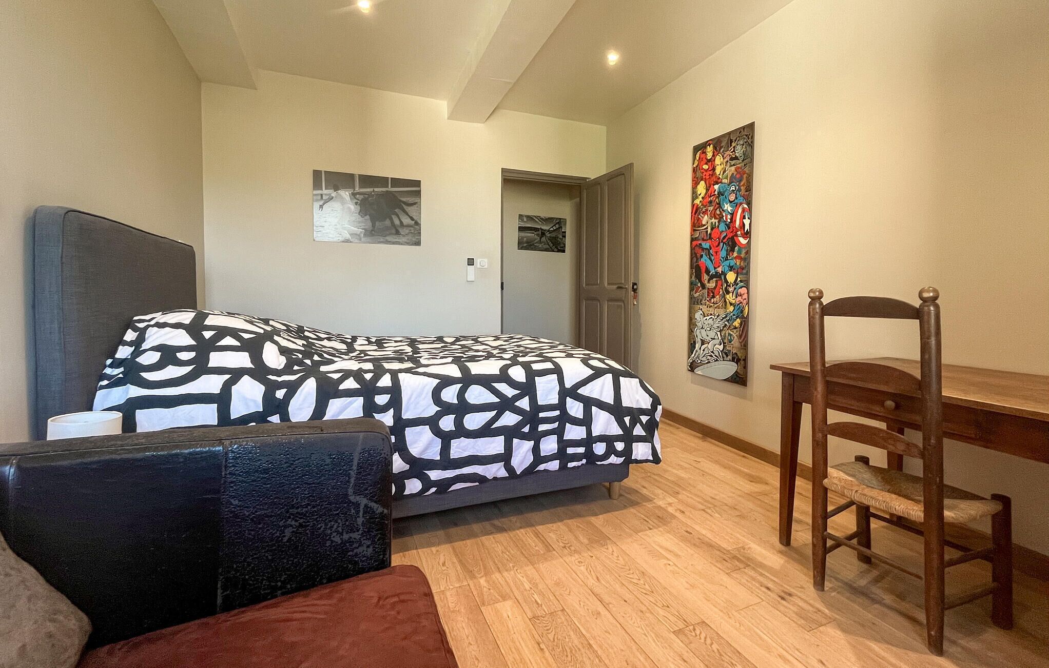 Een slaapkamer met een bed, een stoel, een bureau en een deur.