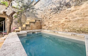 Una piscina con muros de piedra y una escalera de metal.