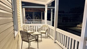 A covered porch with wicker furniture and a railing.