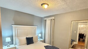 A bedroom with a bed, nightstands, a mirror, and a ceiling light.