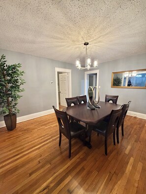 A dining room with a wooden table and chairs, a ceiling fan, and a potted plant.