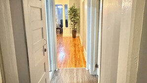 A hallway with wooden flooring, white doors, and a potted plant.