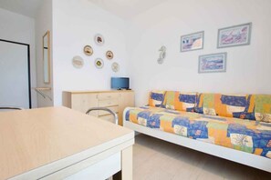Ein Zimmer mit einem Bett, einem Schreibtisch, einem Sessel, einem Fernseher und Wanddekorationen.