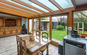 A kitchen with a dining table, chairs, a coffee machine, and a view of the garden through large windows. - Stunning home in Compans with sauna (Compans)
