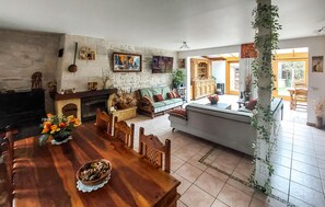 A spacious living area with a fireplace, a dining table, and a kitchen in the background. - Stunning home in Compans with sauna (Compans)