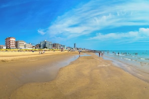 A beach with a pier, sandy shore, and buildings in the background. - Holiday apartment mit Klimaanlage und Balkon (Lido di Jesolo)