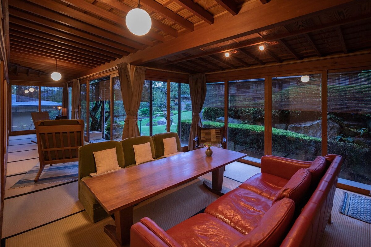 A traditional Japanese-style room with tatami flooring, a low wooden table, and a sofa.