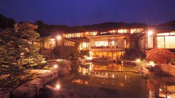 A traditional building with a reflective pond, illuminated by ambient lighting.
