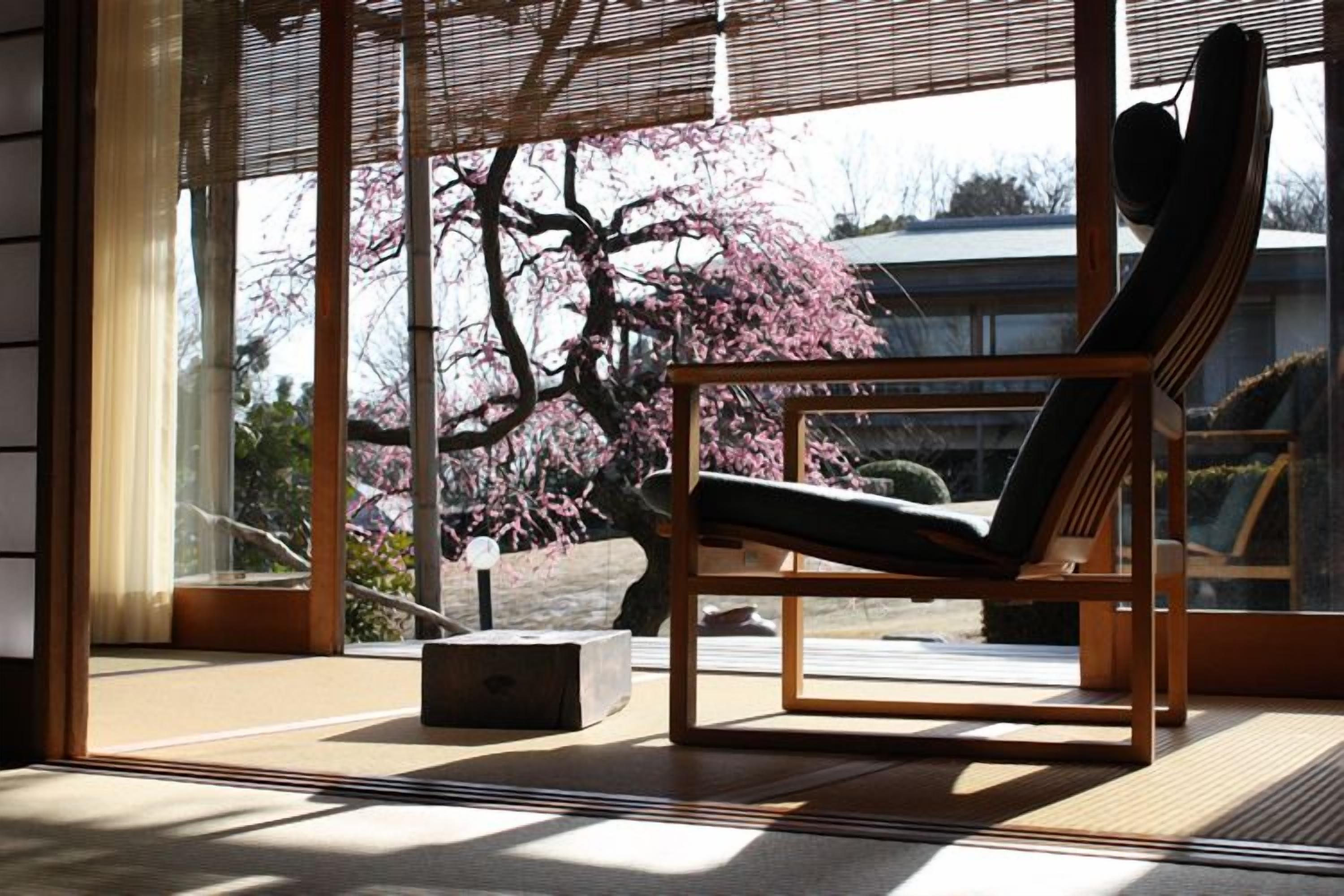 A room with a large window, a wooden chair, and a tatami mat floor.