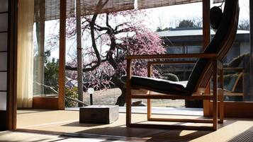 A room with a large window, a wooden chair, and a tatami mat floor.