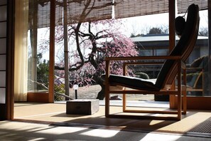 A room with a large window, a wooden chair, and a tatami mat floor. - Miyahama Onsen Teien no Yado Sekitei (Hatsukaichi)