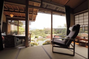 A traditional Japanese-style room with tatami flooring, a low table, and a cushioned chair. - Miyahama Onsen Teien no Yado Sekitei (Hatsukaichi)