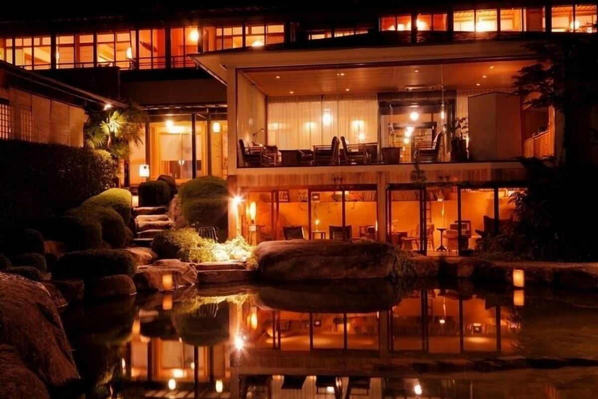 A hotel with a reflective pool, outdoor seating, and a well-lit interior.