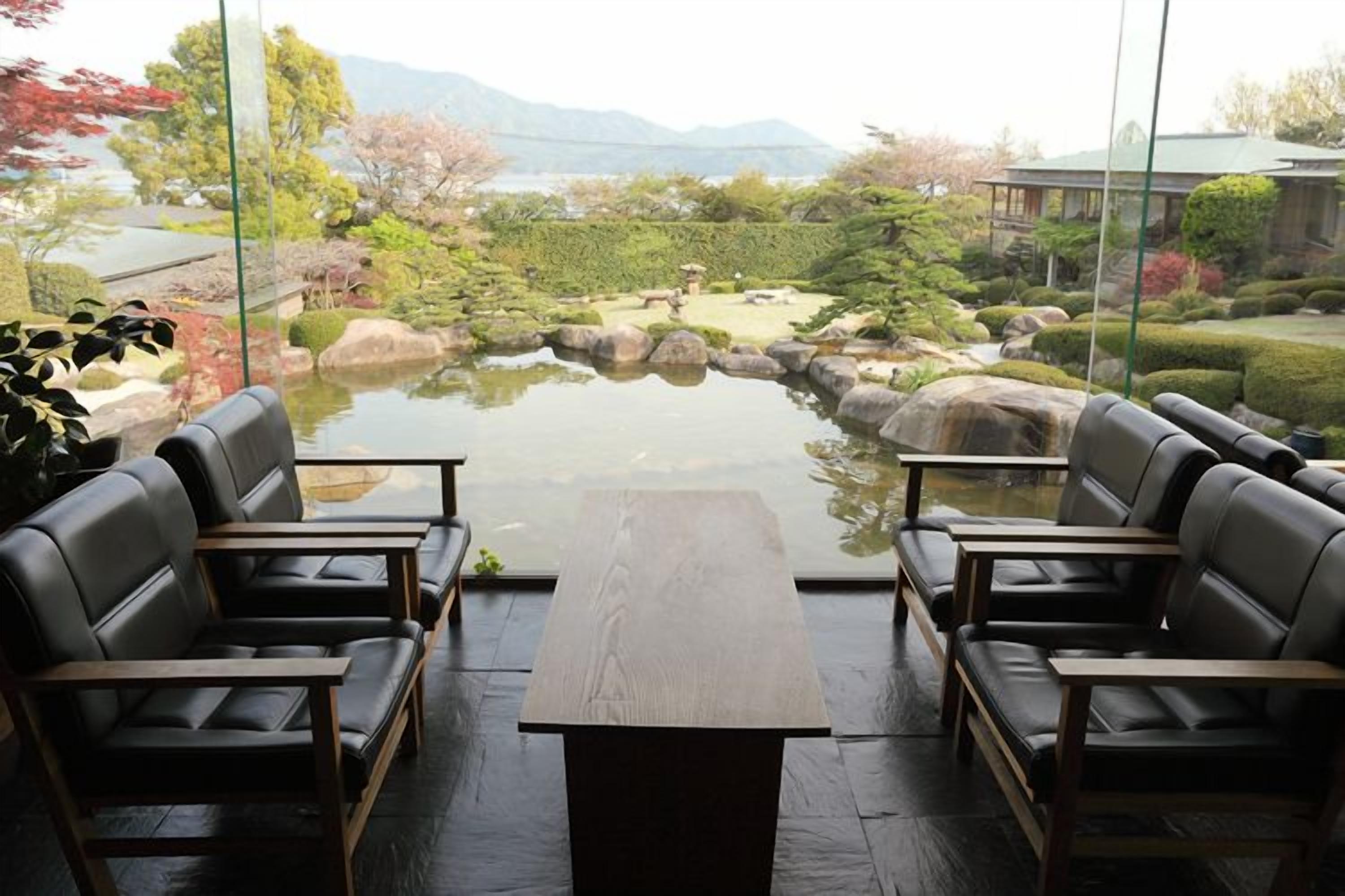 A room with a view of a garden, a table, and four chairs.