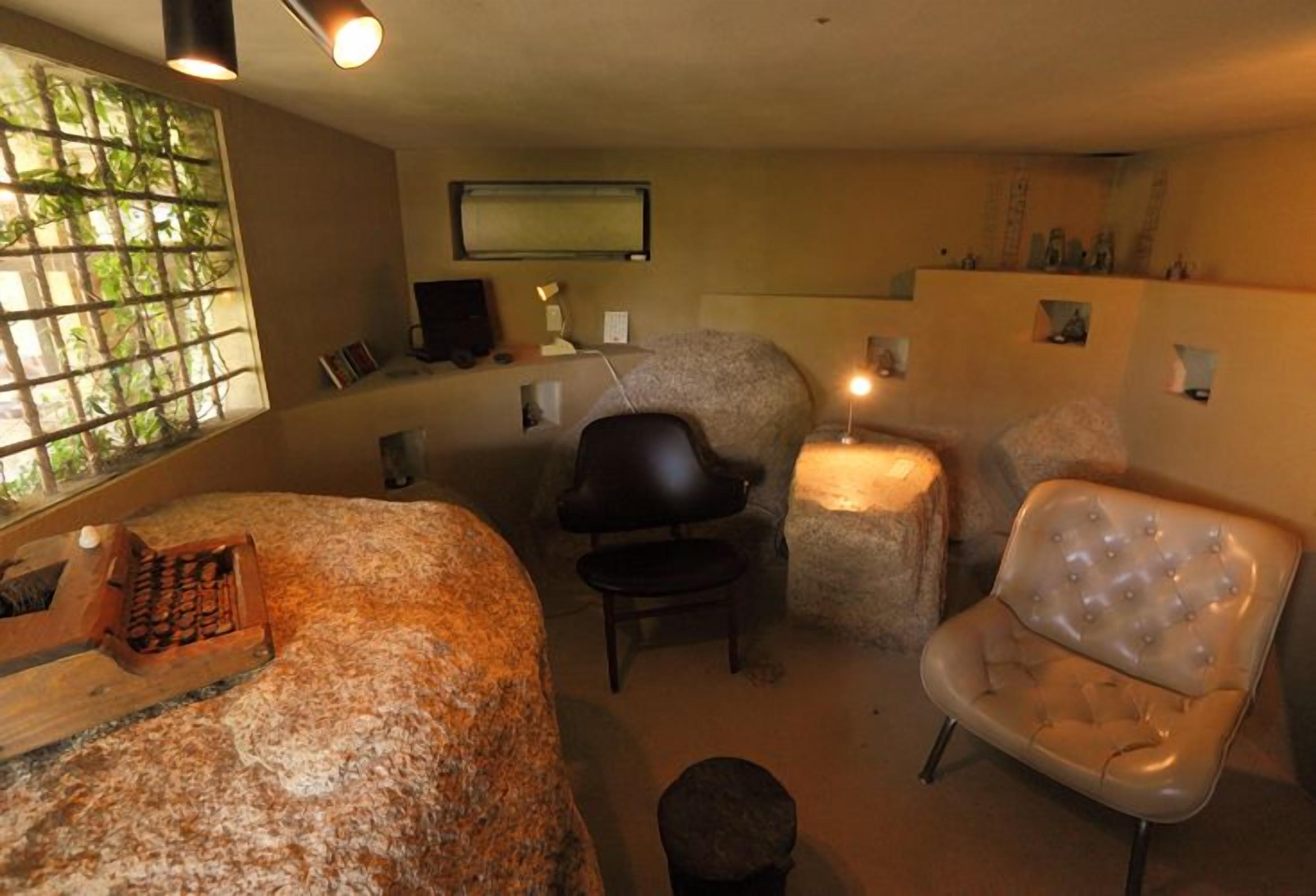 A room with a bed, a chair, a desk, and a television.