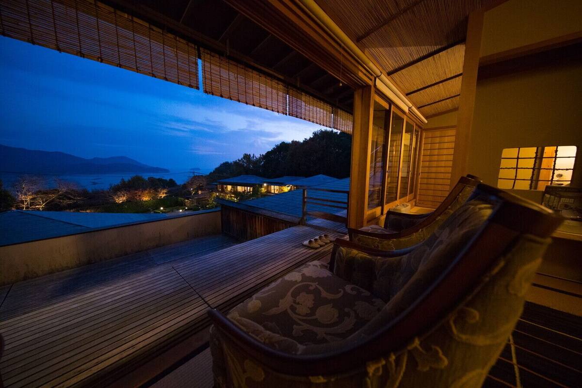 A wooden deck with a view of a lake and mountains at dusk.