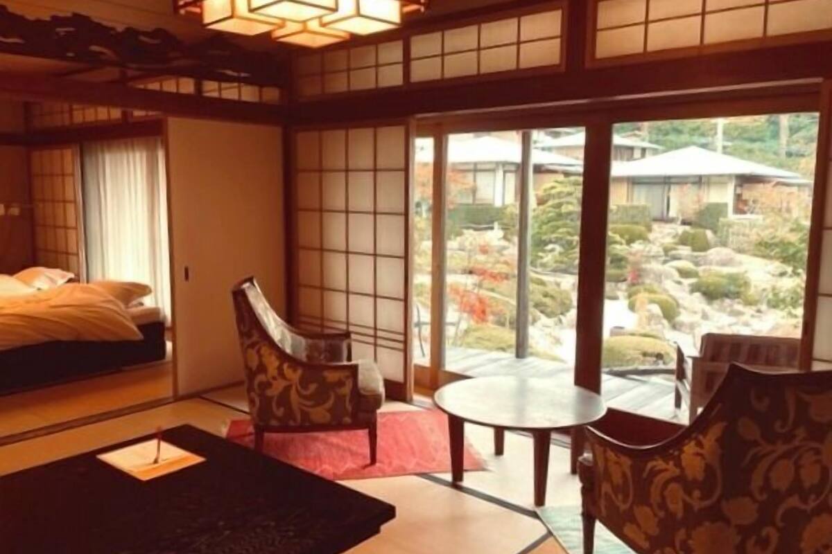A traditional Japanese-style room with tatami flooring, a low table, and chairs.