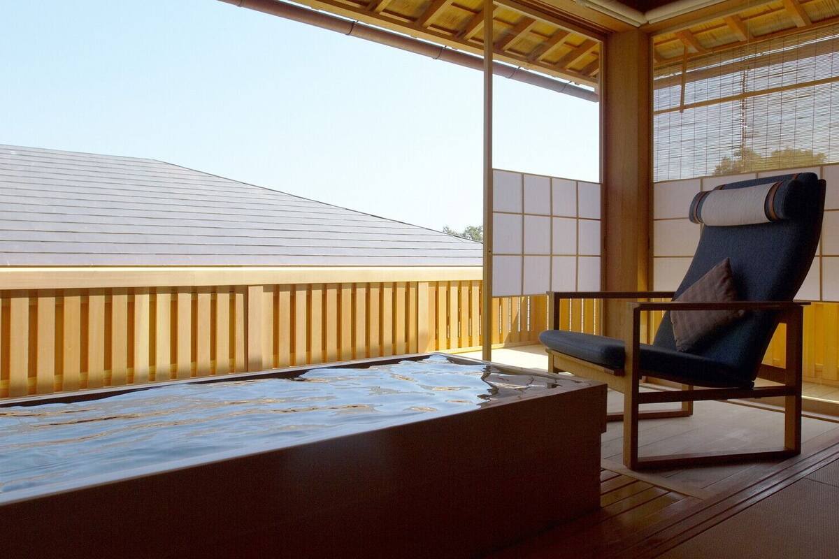 A room with a wooden deck, a chair, and a large window.