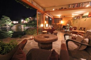 A cozy indoor seating area with a round table, chairs, and a bookshelf filled with books. - Miyahama Onsen Teien no Yado Sekitei (Hatsukaichi)