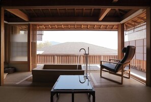 A traditional Japanese room with tatami flooring, a low table, a cushioned bench, and a view of a mountain. - Miyahama Onsen Teien no Yado Sekitei (Hatsukaichi)