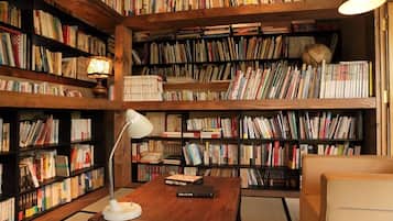 A room with wooden bookshelves filled with books, a desk with a lamp, and a chair.
