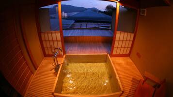 A traditional Japanese onsen with a wooden deck and a view of the landscape.