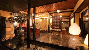 Un intérieur japonais traditionnel avec un sol recouvert de tatamis, une lanterne en pierre et un plafond en bois.