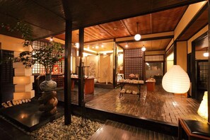 En traditionell japansk inredning med tatamimattor på golvet, en stenlykta och ett träpanelat tak.