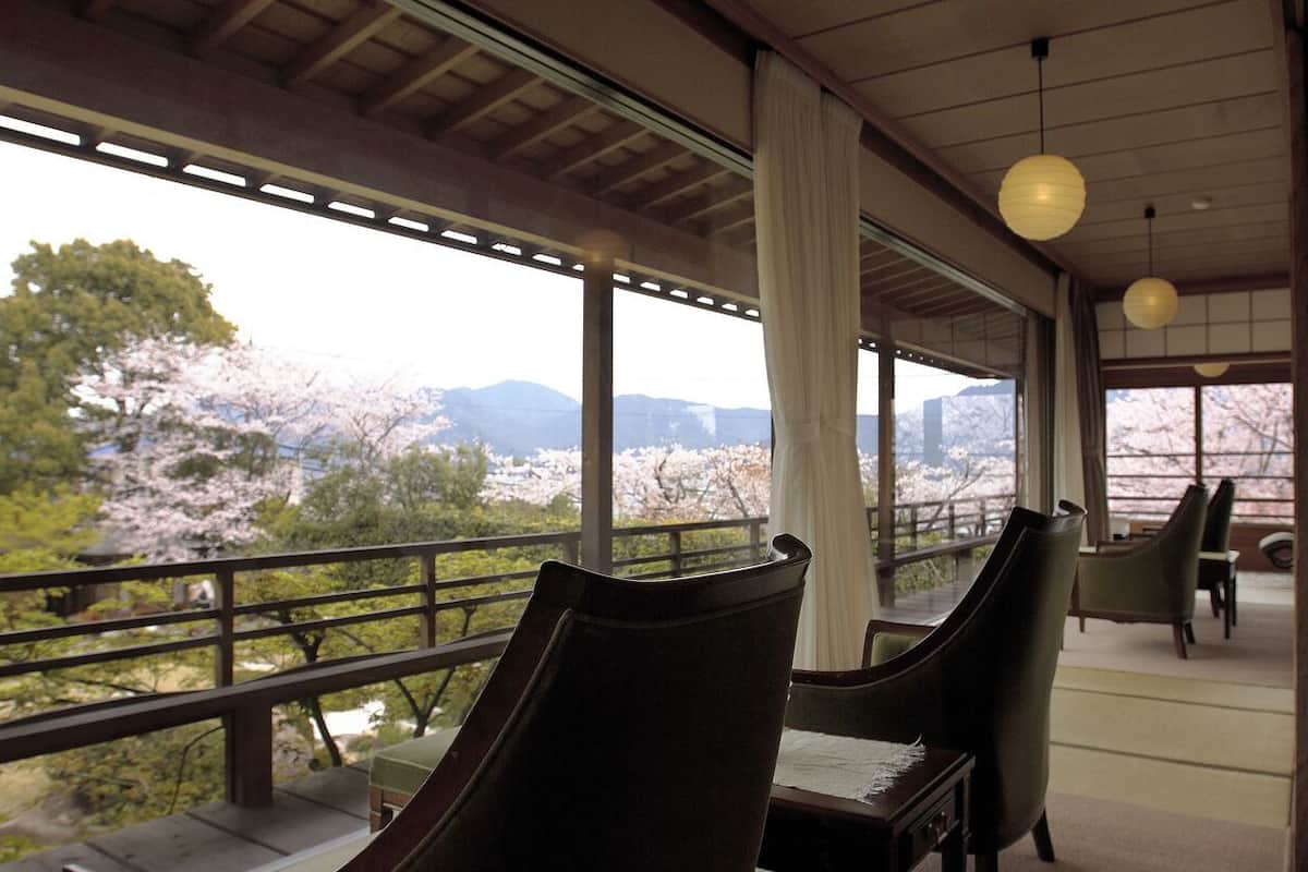 A room with a view of cherry blossoms, wooden furniture, and a traditional ceiling design.