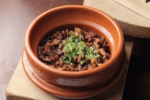 A terracotta bowl filled with a dish, placed on a wooden surface. - Miyahama Onsen Teien no Yado Sekitei (Hatsukaichi)