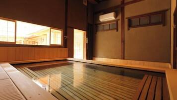 Perinteinen japanilainen onsen-kylpylä, jossa on puulattia, puinen penkki ja liukuvat ovet.