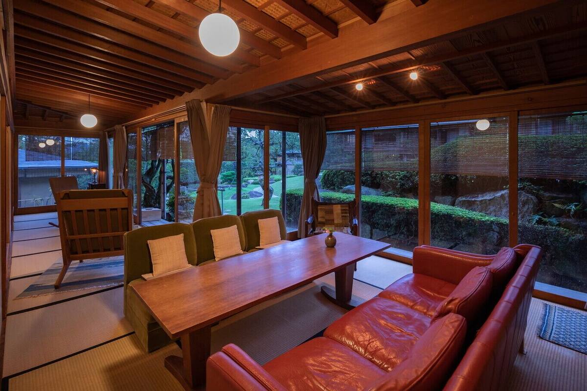 A traditional Japanese-style room with tatami flooring, a low wooden table, and a sofa.