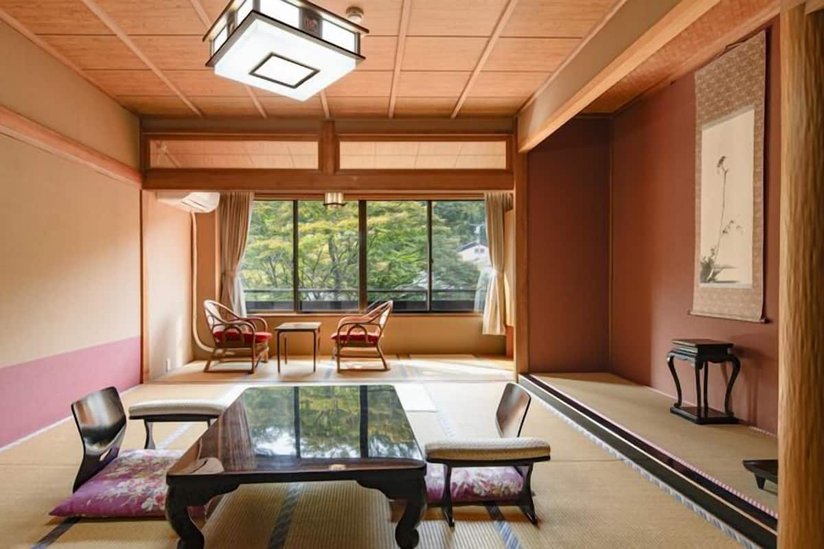 A traditional Japanese room with tatami flooring, a low table, and chairs.