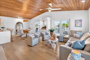 A spacious living area with a wooden ceiling, a dining table, and a sofa set. - Paloma | Canalfront Key Largo Home, Dock, Pool, Porch, Walkable (Key Largo)