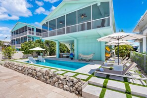 A modern two-story house with a swimming pool, outdoor furniture, and a hammock. - Paloma | Canalfront Key Largo Home, Dock, Pool, Porch, Walkable (Key Largo)