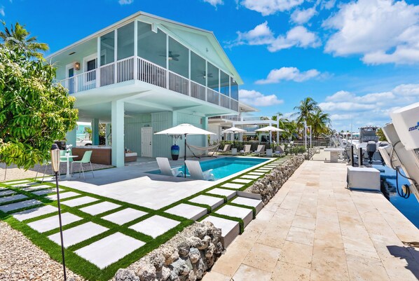 A modern house with a pool, outdoor seating, and a clear blue sky. - Paloma | Canalfront Key Largo Home, Dock, Pool, Porch, Walkable (Key Largo)