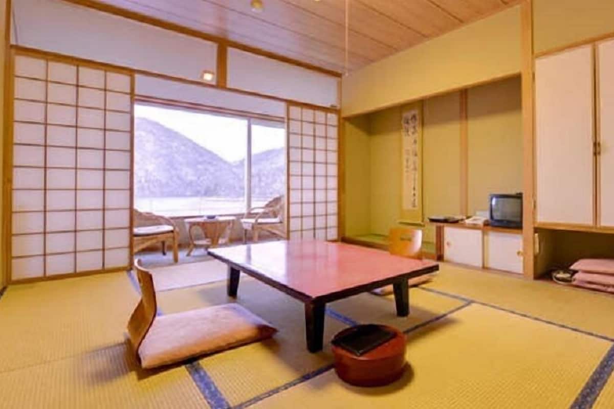 Una habitación japonesa tradicional con suelo de tatami, una mesa baja, un sofá y puertas correderas.