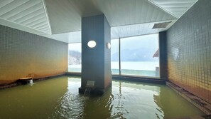 A hot spring bath with tiled walls and a view of a snowy landscape. - Shikaribetsu-kohan Onsen Hotel Fuusui (Shikaoi)