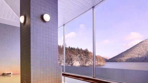 A modern interior with a large window, a tiled wall, and a reflective floor. - Shikaribetsu-kohan Onsen Hotel Fuusui (Shikaoi)